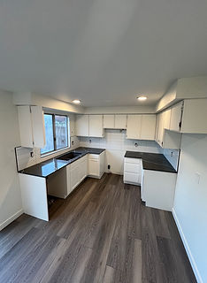 Modern kitchen with white cabinets, dark countertops, and ample natural light.